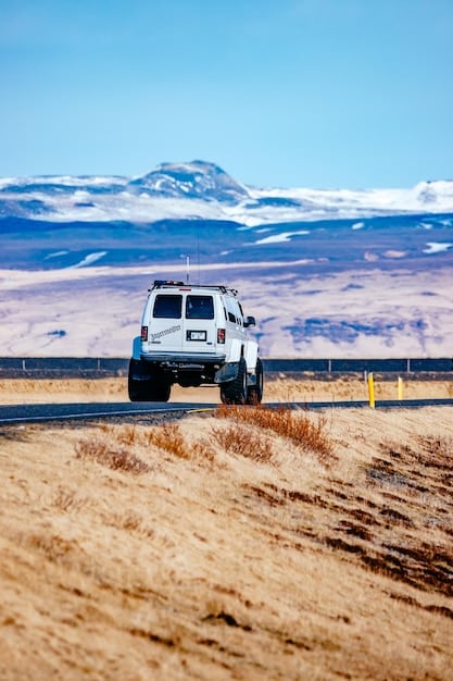 The 2025 GMC Sierra HD driving on a dirt road, showcasing its off-road capabilities with its lifted suspension and rugged tires. The background features a desert landscape.
