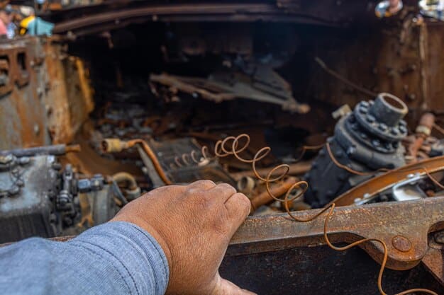 A mechanic's hands pointing at a cracked and worn-out serpentine belt in an engine compartment, with other engine components visible in the background.