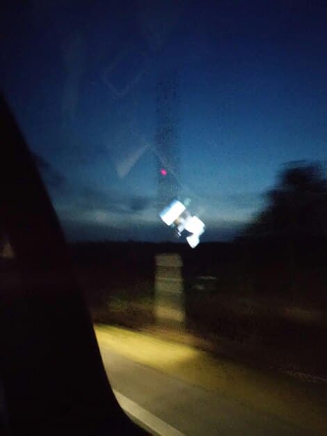 A car driving at night with one headlight restored to clear condition and the other headlight still cloudy, illustrating the difference in light visibility.