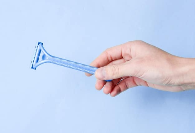 Someone's hands removing an old wiper blade from a car's wiper arm, with the new blade packaging visible in the background.