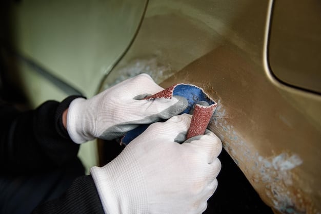 A close-up shot of a person sanding a small rust spot on a car door, using fine-grit sandpaper, preparing it for rust converter application.