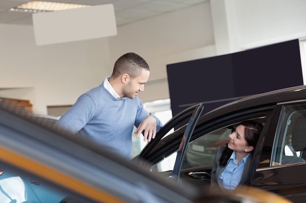 Interior of a modern car dealership with both new and used cars on display, salespeople assisting customers, and digital screens showcasing vehicle information. Clean and well-lit environment.