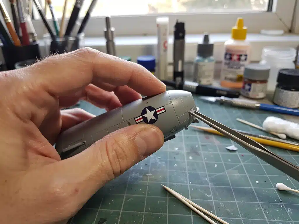 Modeler applying custom decal to scale model aircraft