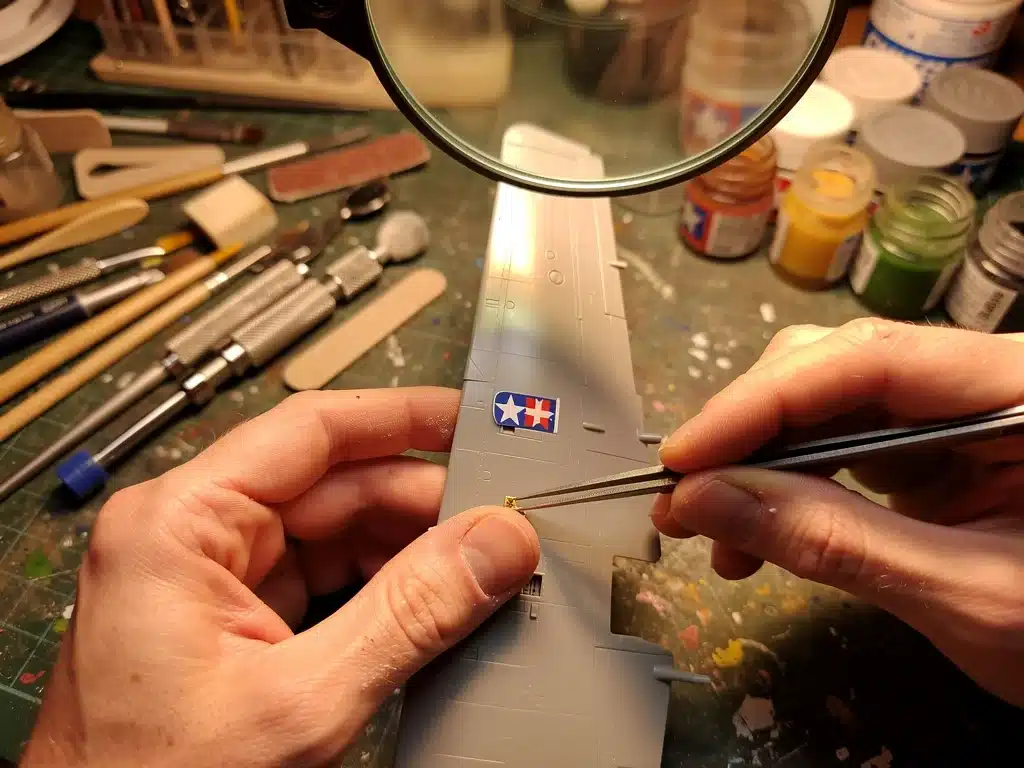 Model builder applying decals with precision tools